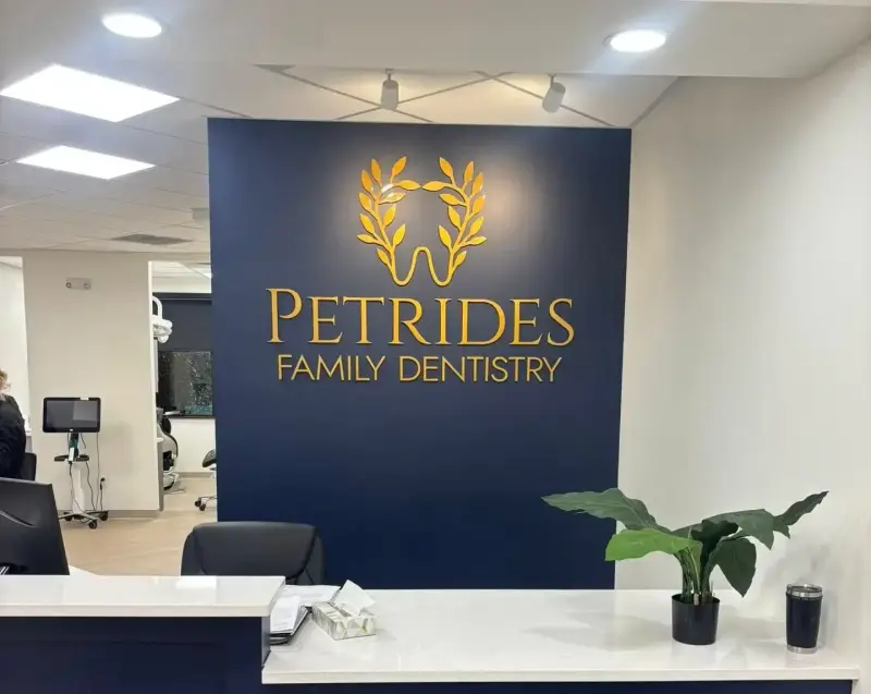 Gold dimensional logo and lettering on a navy wall at Petrides Family Dentistry